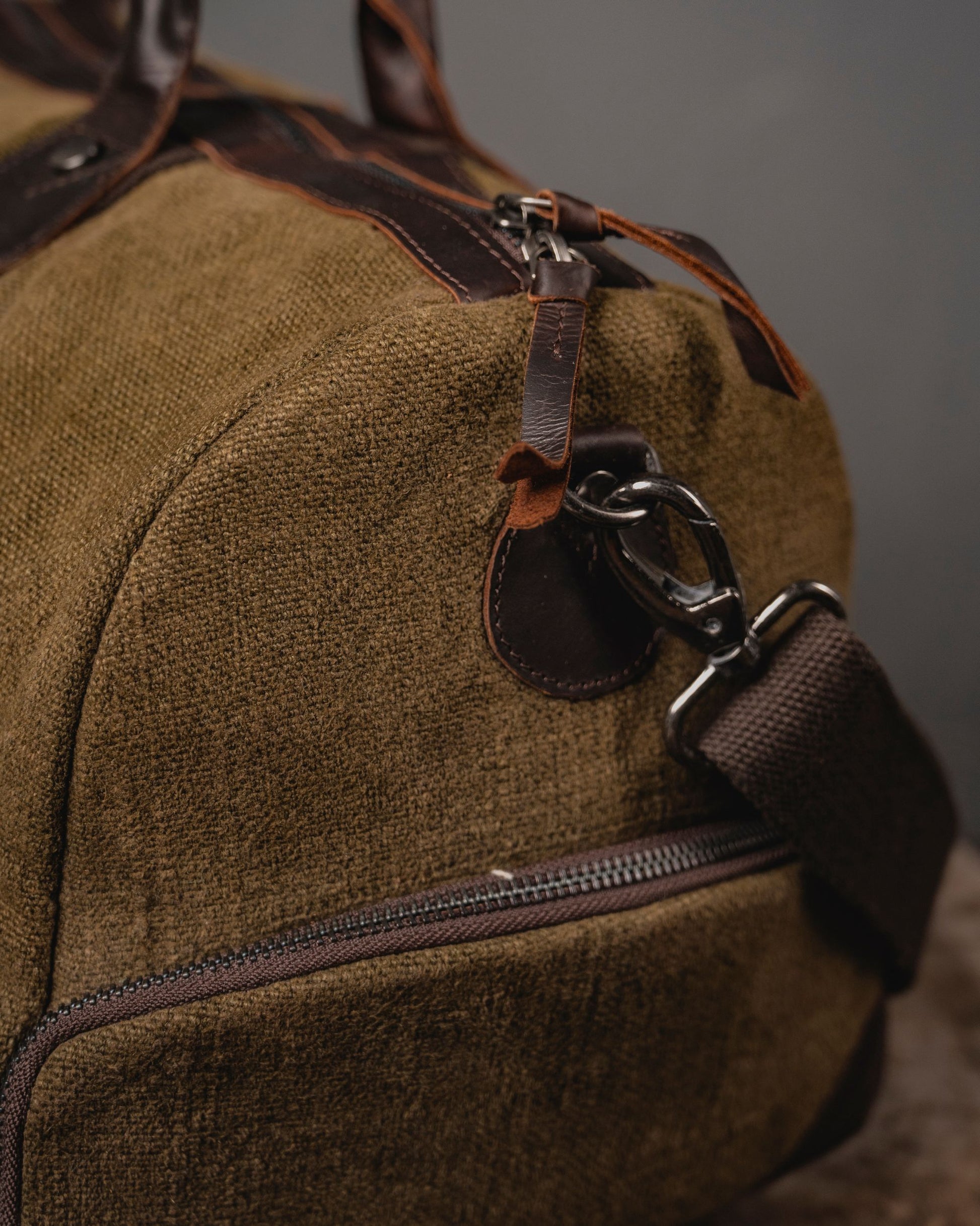 Close-up of antique brass dog hook and leather strap attachment on Brown Mini Duffel 2.0 showing 660 GSM burlap canvas texture and YKK zipper.