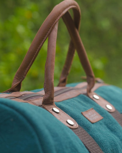 Close up of tan leather handle antique brass rivets and zipper on Mini Duffel 2.0 in Bottle Green