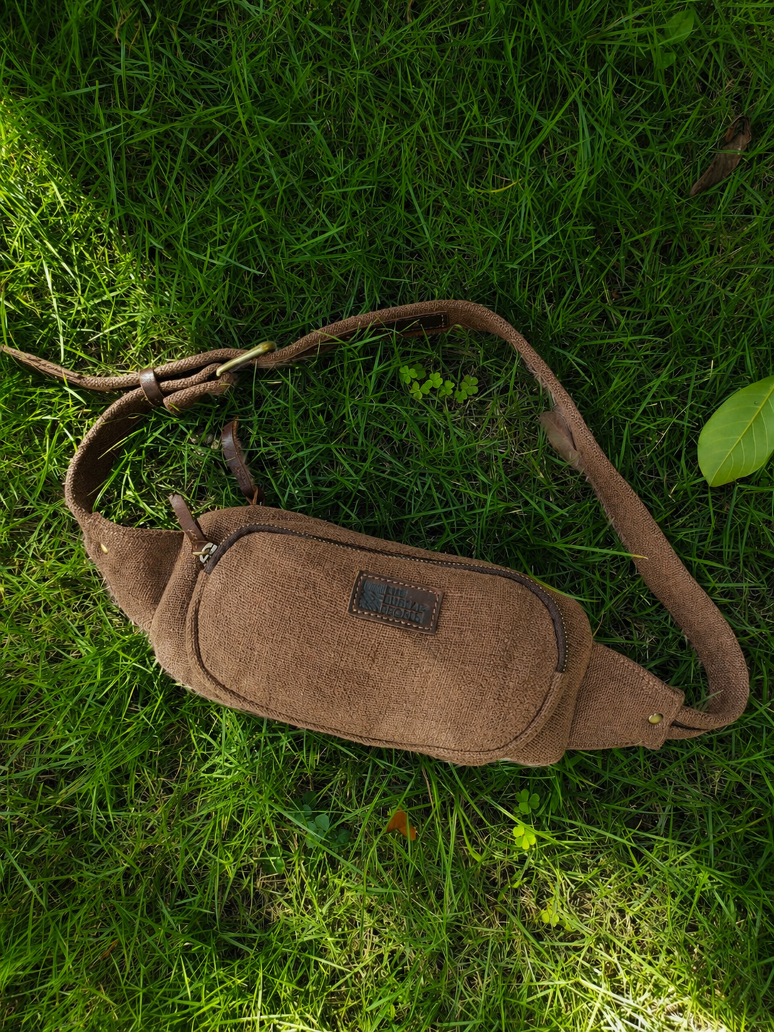 Brown burlap fanny pack laid flat on grass in a natural outdoor setting