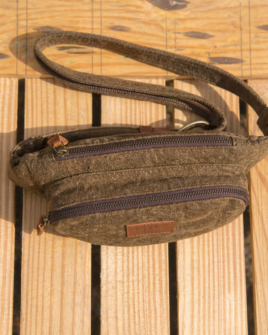 Top view of a brown burlap fanny pack on a wooden crate showing the main compartment front pocket zipper details and leather pullers