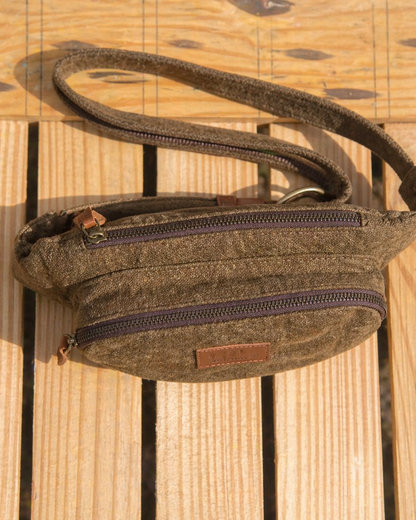Top view of a brown burlap fanny pack on a wooden crate showing the main compartment front pocket zipper details and leather pullers